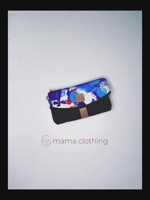 The All Rounder Change Mat shown laying folded up with sand coloured wrist strap. Black rectangular clutch with zebra print curved closing and sand coloured square badge, wrist strap and zip handle.