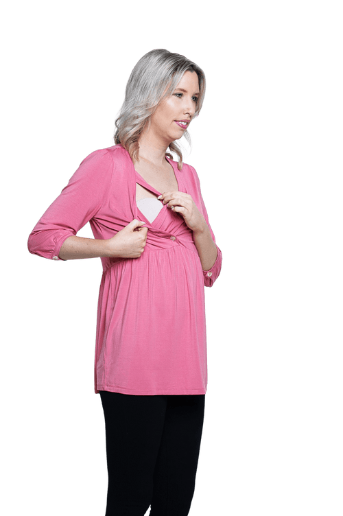Petite model facing camera wearing pink, mid-length sleeved top. Features button up v-neckline and peplum tier under bust. Dylan available in sizes 6-26