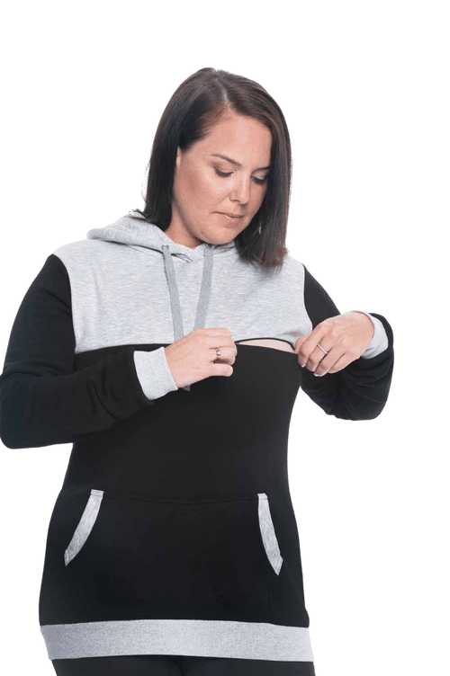Curvy model facing camera wearing black hoodie with grey panel over chest, shoulders, and top of back, featuring front pocket, and grey highlights at pocket openings and sleeve cuffs. Olivia hoodie available in sizes 6-26