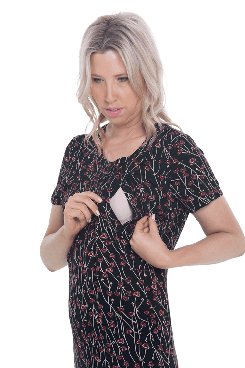 Petite model facing camera wearing black with small red rose patterned mid thigh length nightie, featuring rounded neckline, scooped hemline with short sleeves. Penny available in sizes 6-18