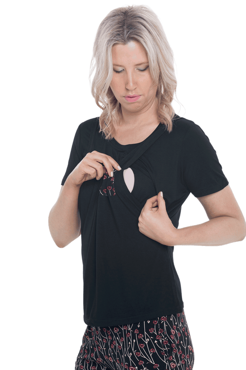 Curvy model facing camera wearing short sleeved pyjamas with shorts. Top is black with contrast breast pocket matching shorts. Shorts are black with small red rose pattern, featuring pockets, and elasticated waist with pull tie. Poppy available in sizes 6-26