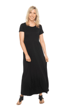 Petite model facing the camera wearing black maxi dress, featuring  rounded neckline, and a gently fitted bodice, gathering above the waist. Riley available in sizes 6-26