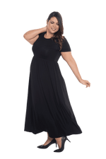 Curvy model facing the side wearing black maxi dress, featuring  rounded neckline, and a gently fitted bodice, gathering above the waist. Riley available in sizes 6-26