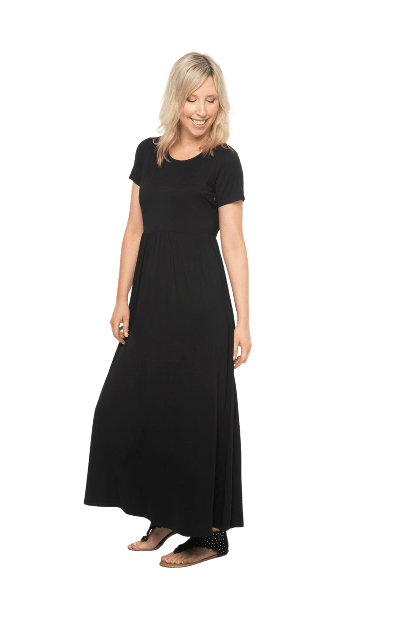 Petite model facing the side wearing black maxi dress, featuring  rounded neckline, and a gently fitted bodice, gathering above the waist. Riley available in sizes 6-26