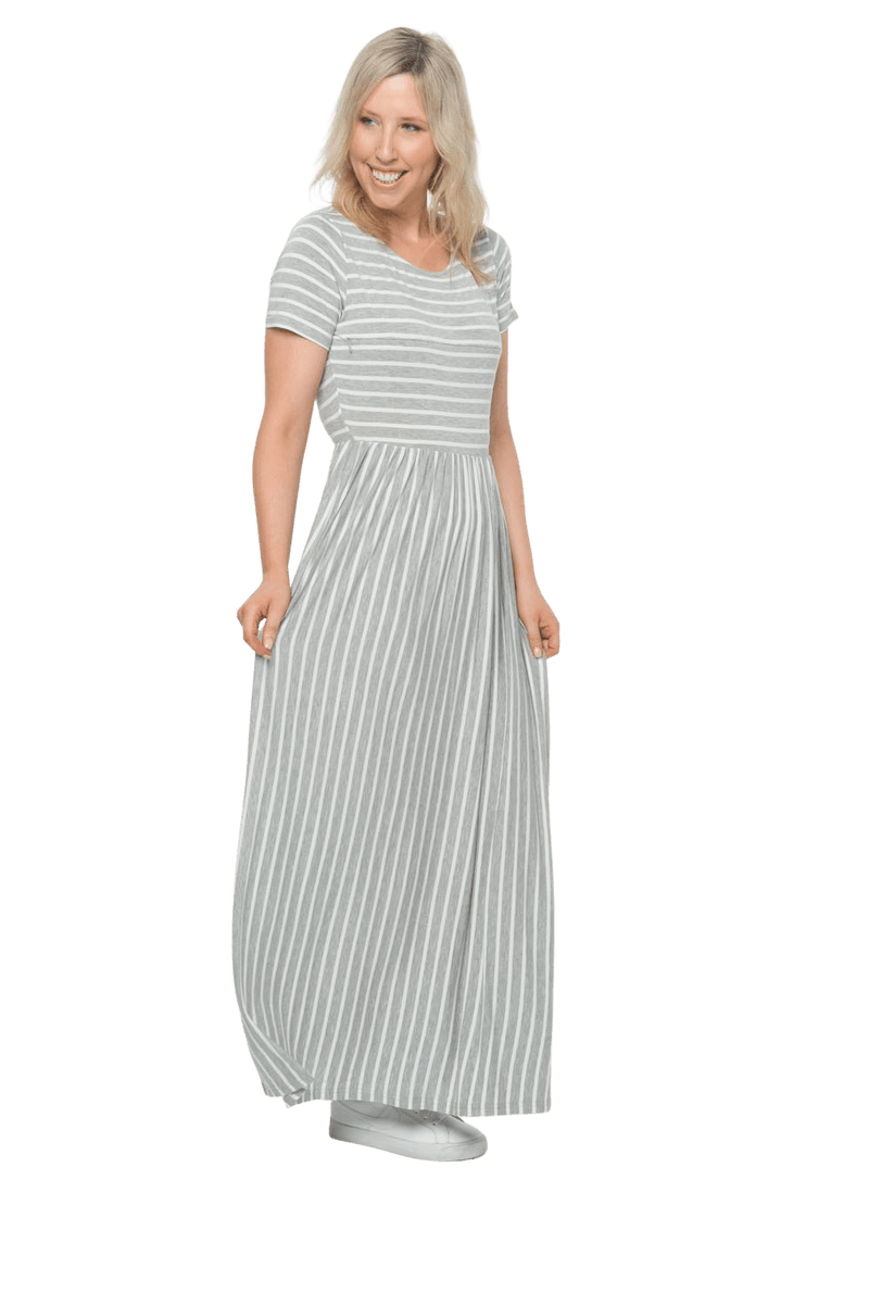 Petite model facing the side wearing light grey and white striped maxi dress, featuring rounded neckline, and a gently fitted bodice, gathering above the waist. Riley available in sizes 6-18