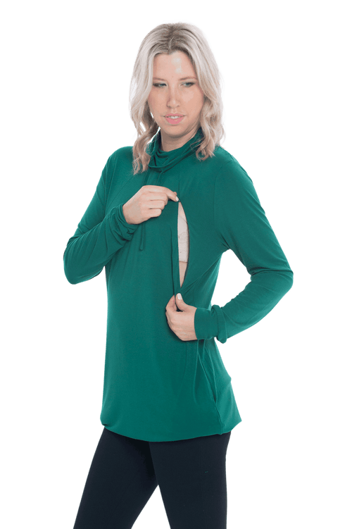 Curvy model facing the camera wearing bottle green long sleeved tunic as a dress with boots, featuring pockets and a faux hoodie collar in a comfy, relaxed fit. Tori available in sizes 6-26