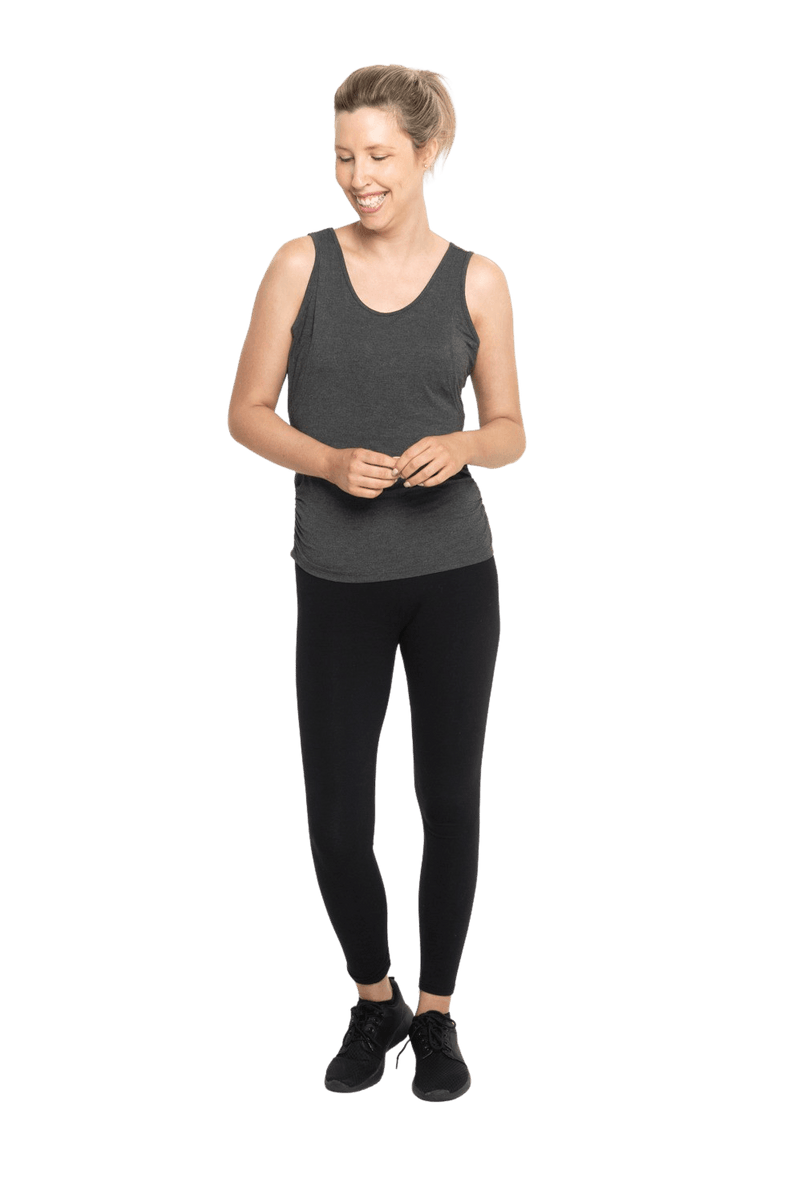 Petite model facing camera wearing charcoal grey tank top, featuring rounded neckline and side rouching. Adrien available in sizes 6-26
