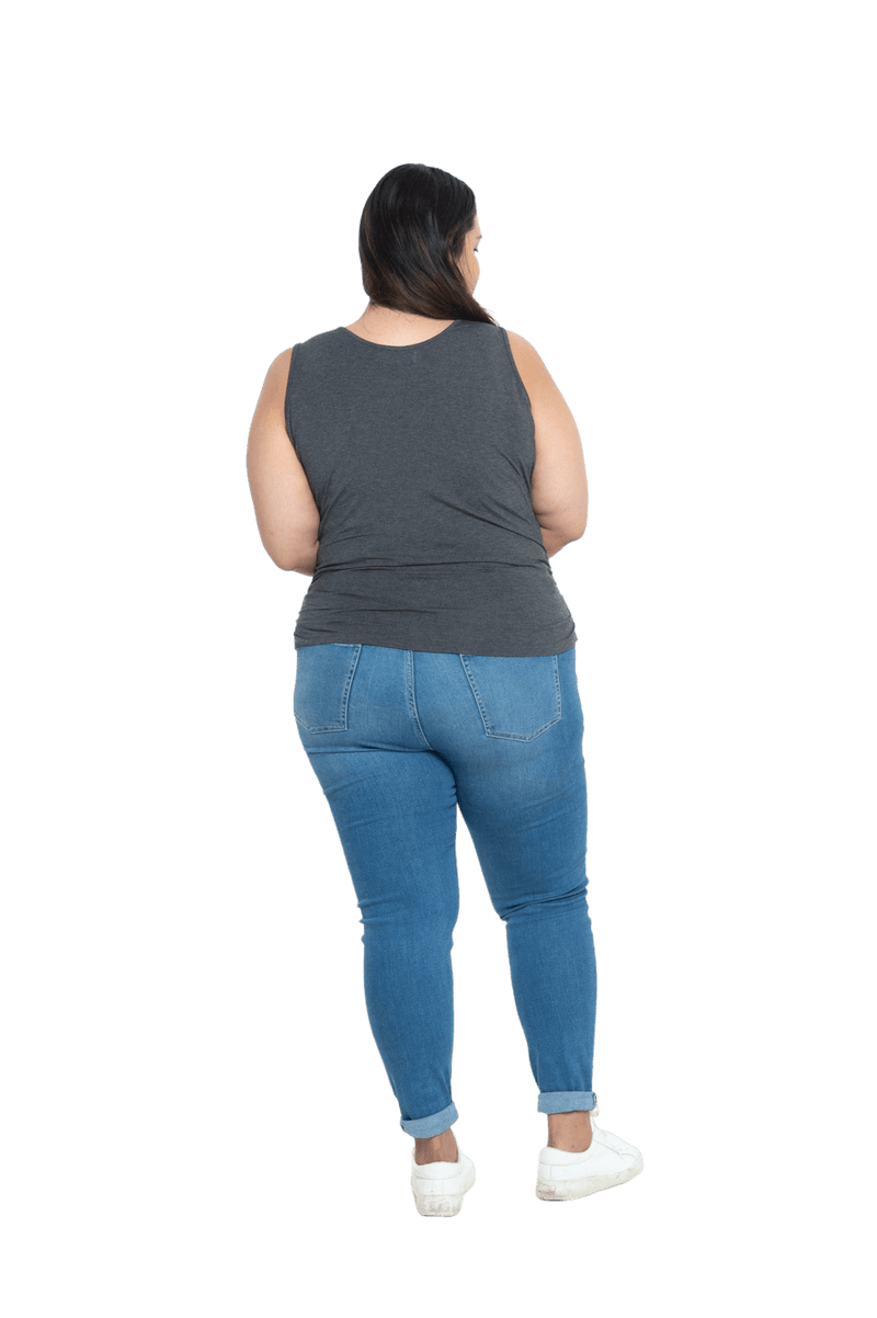 Curvy model facing the back wearing charcoal grey tank top, featuring rounded neckline and side rouching. Adrien available in sizes 6-26
