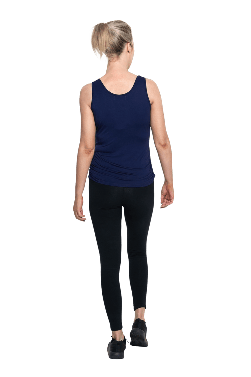 Petite model facing the back wearing navy blue tank top, featuring rounded neckline and side rouching. Adrien available in sizes 6-26