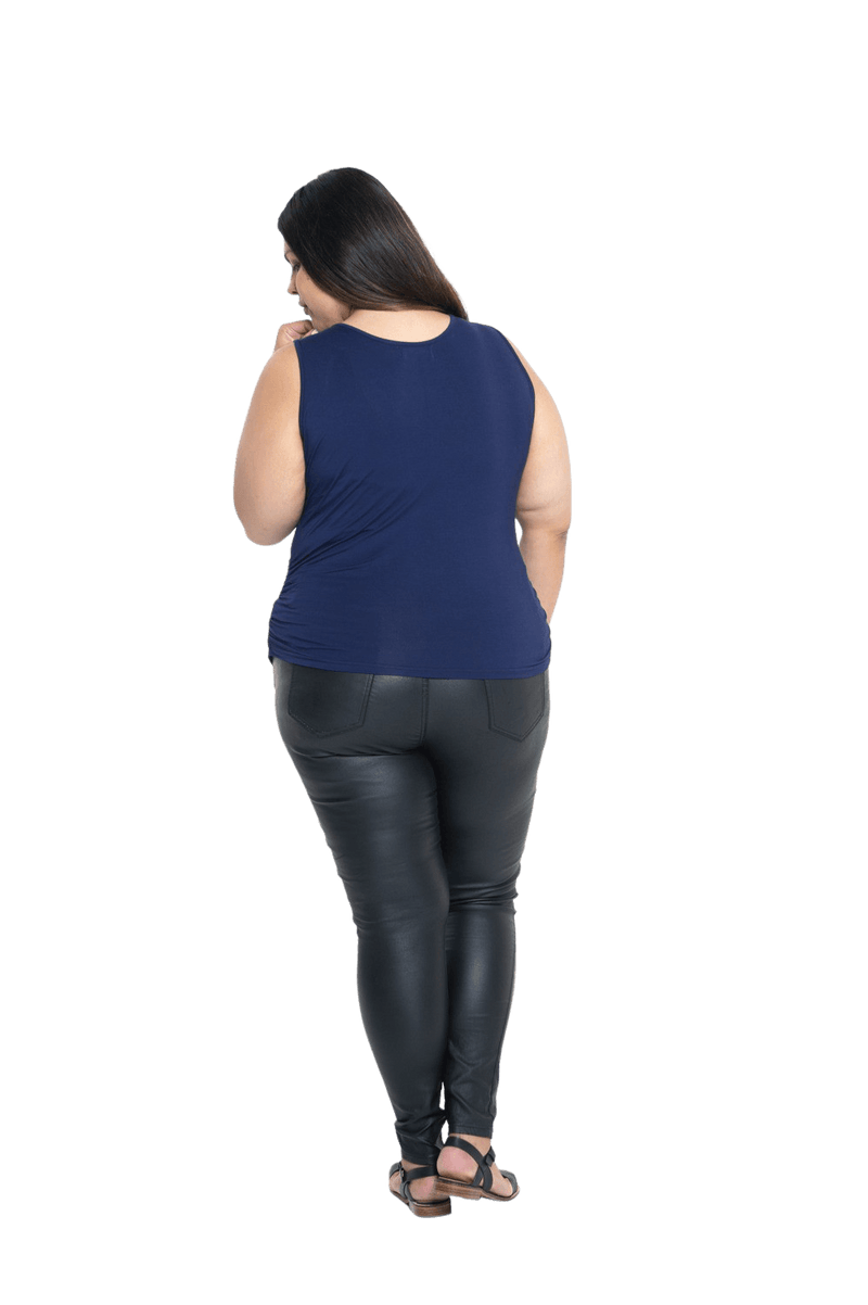 Curvy model facing the back wearing navy blue tank top, featuring rounded neckline and side rouching. Adrien available in sizes 6-26