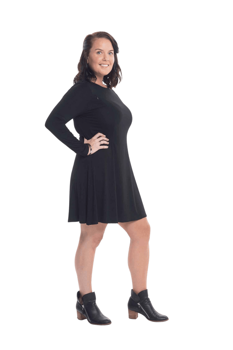 Brunette model facing camera wearing black A-line swing dress, featuring rounded neckline. Amber available in sizes 6-26