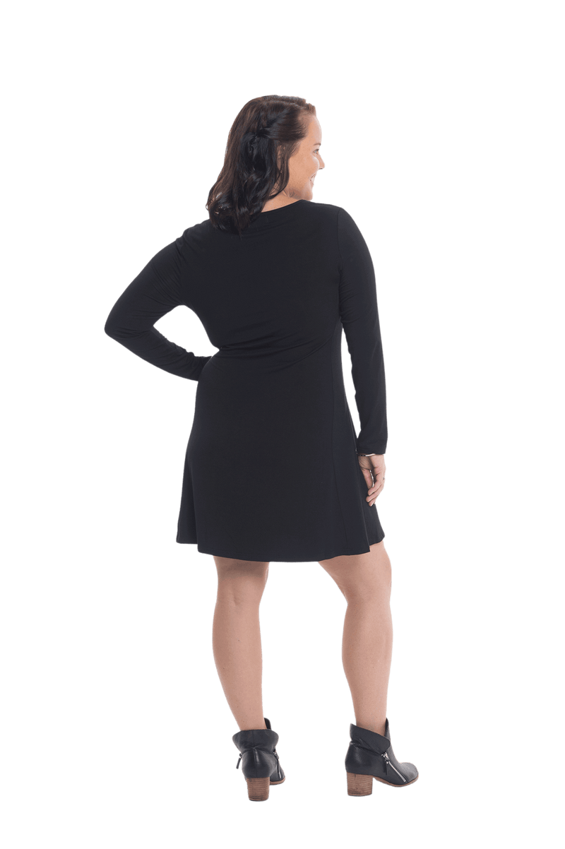 Petite model facing the side wearing black A-line swing dress, featuring rounded neckline. Amber available in sizes 6-26