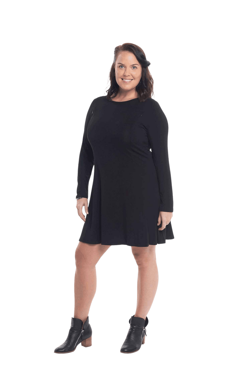 Brunette model facing the side wearing black A-line swing dress, featuring rounded neckline. Amber available in sizes 6-26