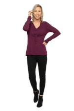 Petite model facing camera wearing burgundy, long sleeved, v-neck top, features small tie front under bust. Billie available in sizes 6-26