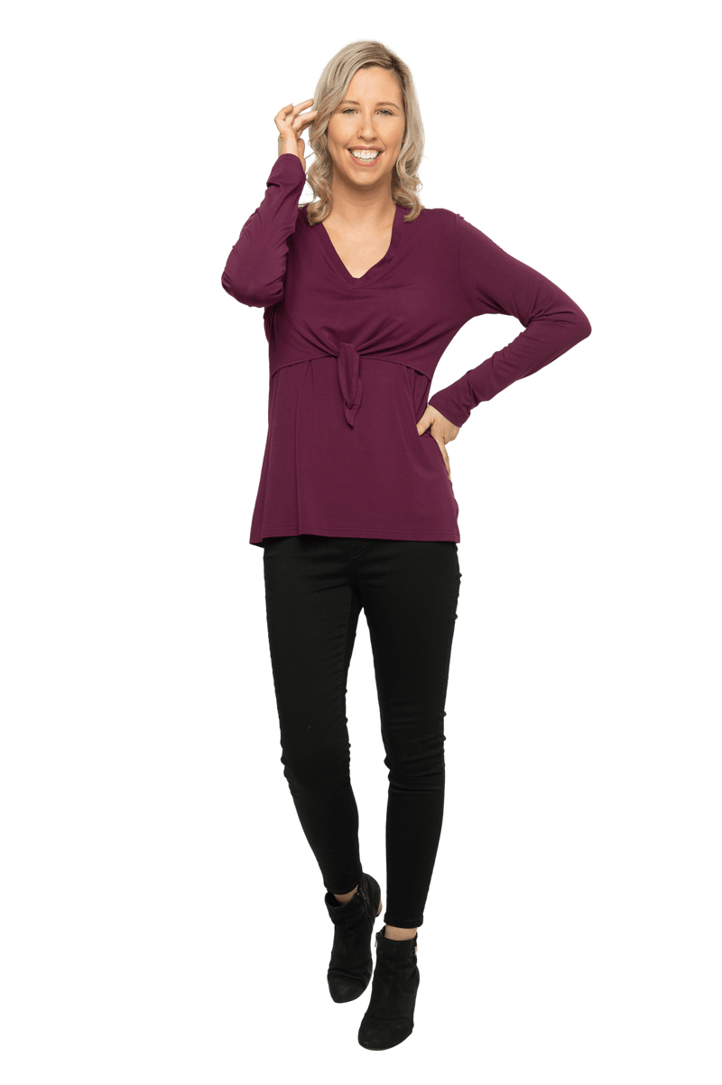 Petite model facing camera wearing burgundy, long sleeved, v-neck top, features small tie front under bust. Billie available in sizes 6-26