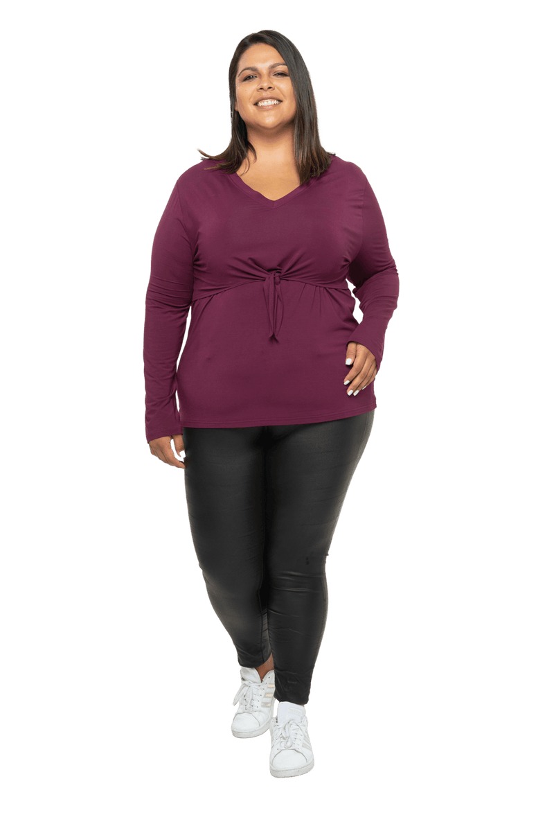 Curvy model facing camera wearing burgundy, long sleeved, v-neck top, features small tie front under bust. Billie available in sizes 6-26