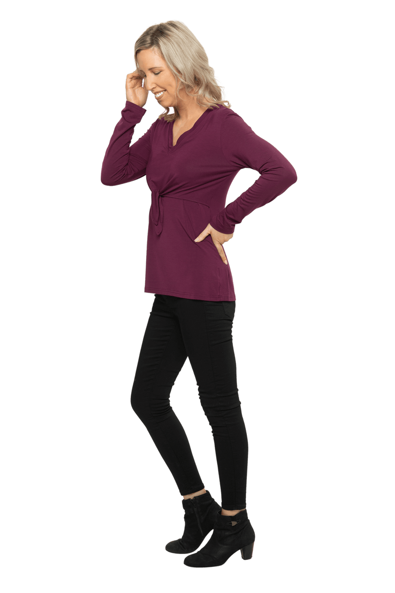Petite model facing the side wearing burgundy, long sleeved, v-neck top, features small tie front under bust. Billie available in sizes 6-26