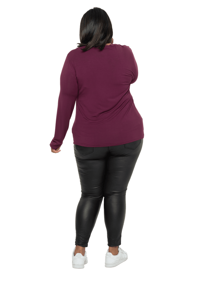 Curvy model facing the back wearing burgundy, long sleeved, v-neck top, features small tie front under bust. Billie available in sizes 6-26