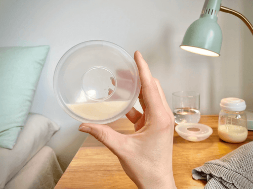 Breastmilk collection shell filled with milk with bedroom background