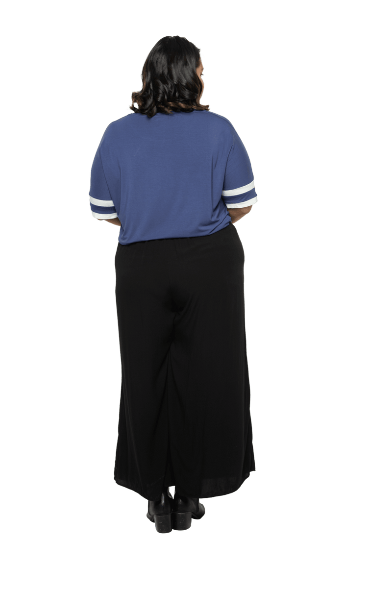 Curvy model facing the back wearing navy blue, short sleeved, relaxed fit top, features rounded neckline and two white varsity stripes on the sleeve. Cameron available in sizes 6-26