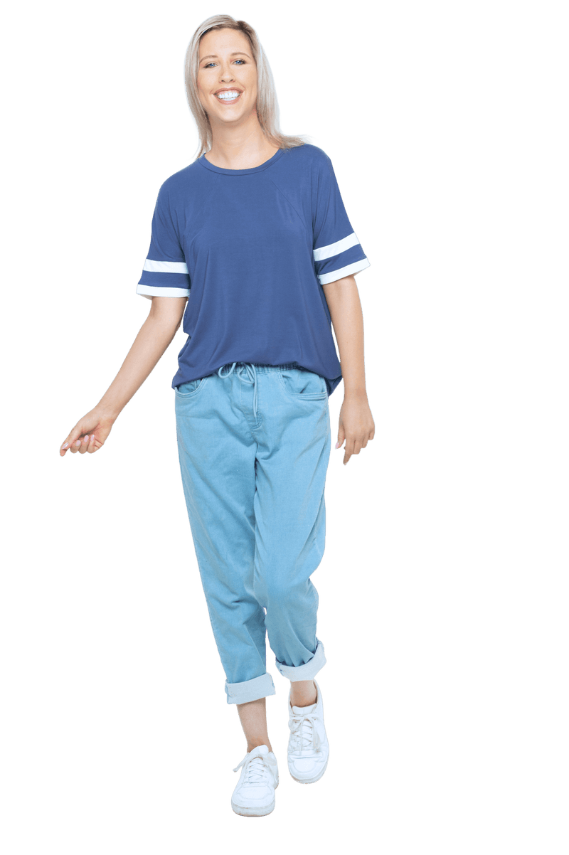 Petite model facing camera wearing navy blue, short sleeved, relaxed fit top, features rounded neckline and two white varsity stripes on the sleeve. Cameron available in sizes 6-26