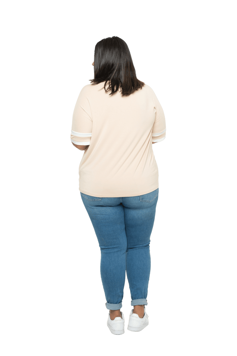 Curvy model facing the back wearing sand, short sleeved, relaxed fit top, features rounded neckline and two white varsity stripes on the sleeve. Cameron available in sizes 6-26
