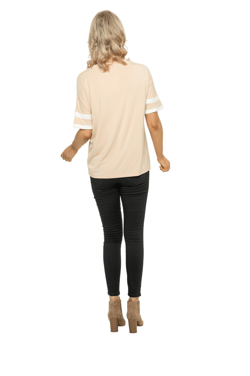 Petite model facing the back wearing sand, short sleeved, relaxed fit top, features rounded neckline and two white varsity stripes on the sleeve. Cameron available in sizes 6-26