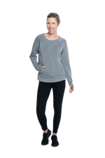 Petite model facing camera wearing grey crew necked jumper, featuring thick, flat waist band, thumb holes, and pockets. Cassie available in sizes 6-26