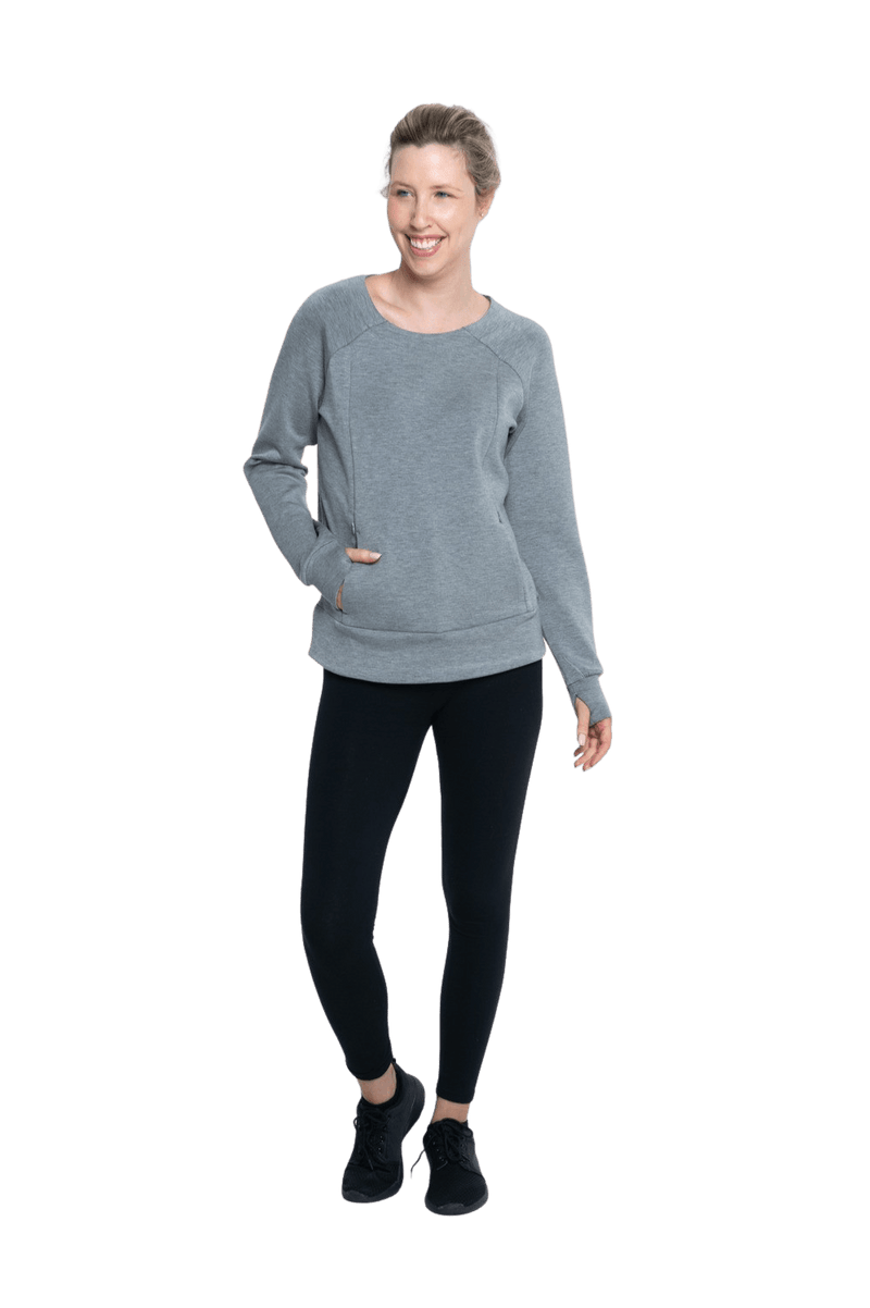 Petite model facing camera wearing grey crew necked jumper, featuring thick, flat waist band, thumb holes, and pockets. Cassie available in sizes 6-26