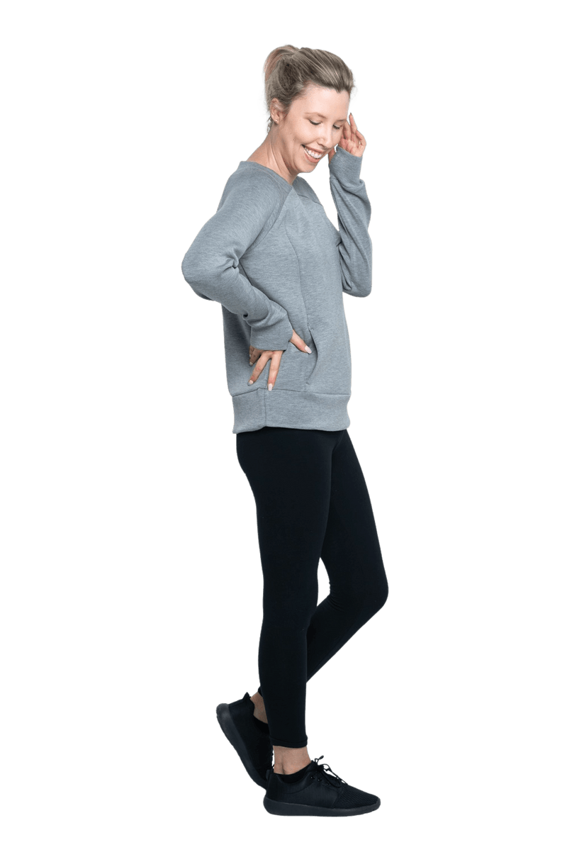 Petite model facing the side wearing grey crew necked jumper, featuring thick, flat waist band, thumb holes, and pockets. Cassie available in sizes 6-26