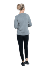 Petite model facing the back wearing grey crew necked jumper, featuring thick, flat waist band, thumb holes, and pockets. Cassie available in sizes 6-26
