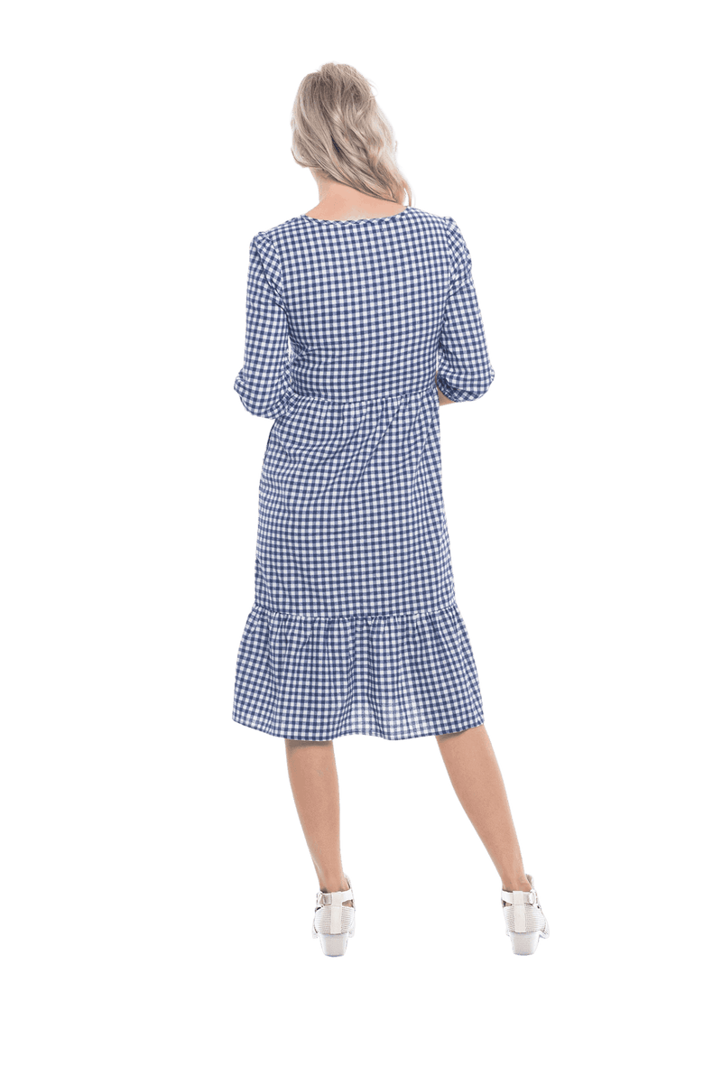 Model facing the back wearing blue gingham, mid-length sleeved midi dress, features rounded neckline, tiered skirt and pockets. Dorothy available in sizes 6-18