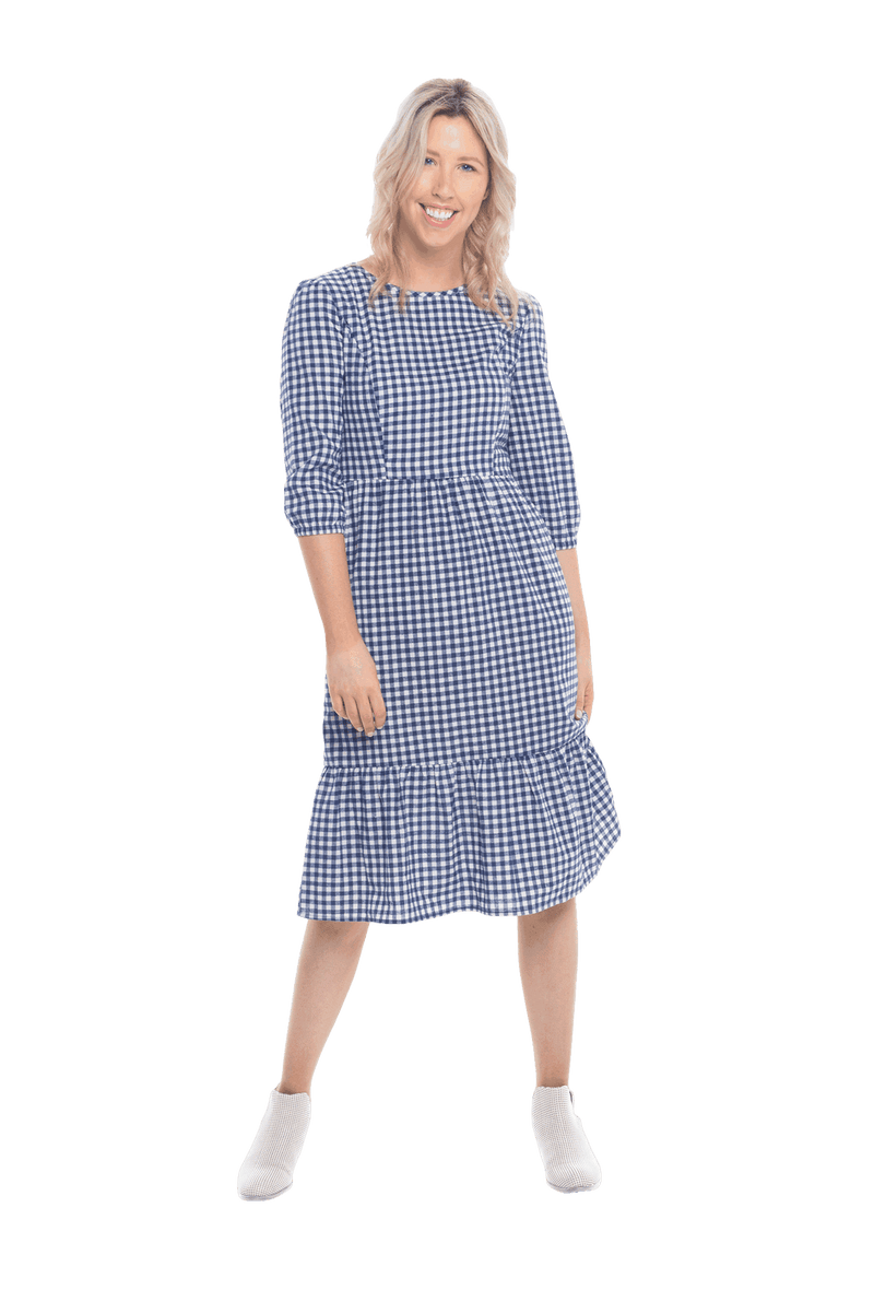Model facing camera wearing blue gingham, mid-length sleeved midi dress, features rounded neckline, tiered skirt and pockets. Dorothy available in sizes 6-18