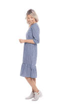 Model facing the side wearing blue gingham, mid-length sleeved midi dress, features rounded neckline, tiered skirt and pockets. Dorothy available in sizes 6-18