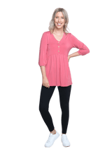 Petite model facing camera wearing pink, mid-length sleeved top. Features button up v-neckline and peplum tier under bust. Dylan available in sizes 6-26
