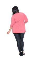 Curvy model facing the back wearing pink, mid-length sleeved top. Features button up v-neckline and peplum tier under bust. Dylan available in sizes 6-26