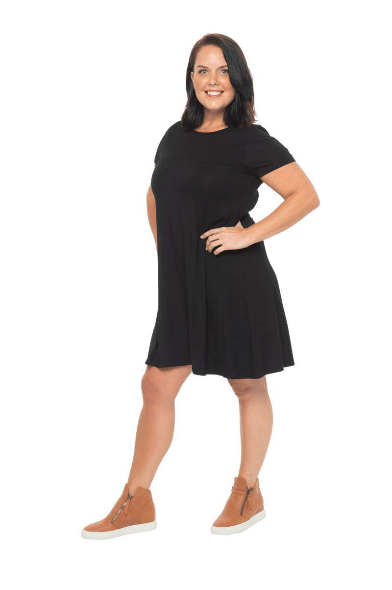 Model facing the side wearing black, short sleeved, knee length, A-line dress. Features rounded neckline. Emma available in sizes 6-18