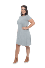 Model facing the side wearing grey, short sleeved, knee length, A-line dress. Features rounded neckline. Emma available in sizes 6-18