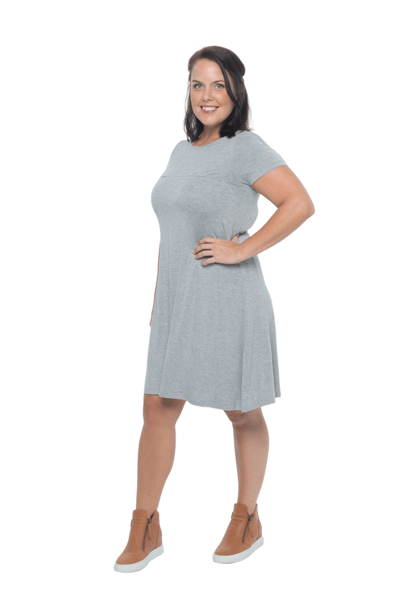 Model facing the side wearing grey, short sleeved, knee length, A-line dress. Features rounded neckline. Emma available in sizes 6-18