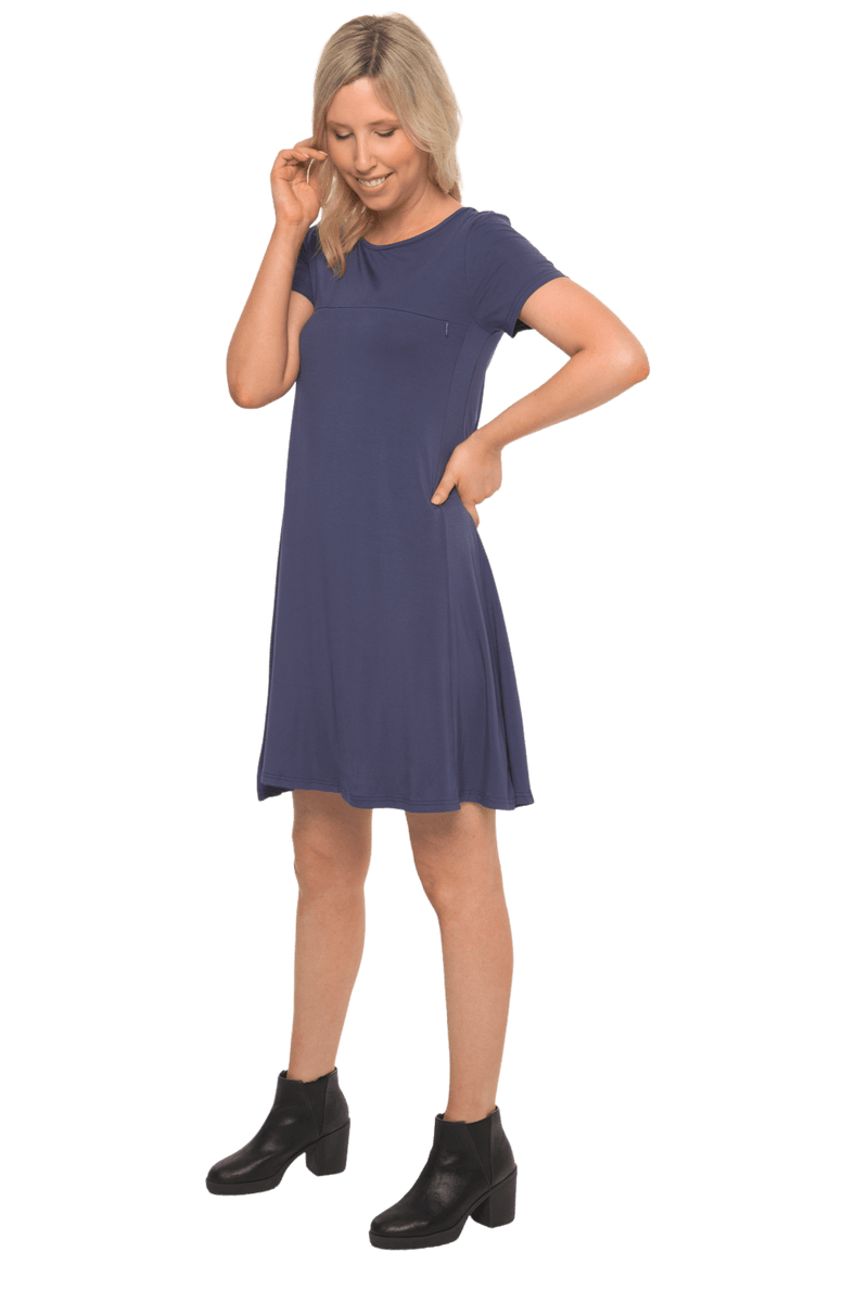 Model facing camera wearing navy blue, short sleeved, knee length, A-line dress. Features rounded neckline. Emma available in sizes 6-18