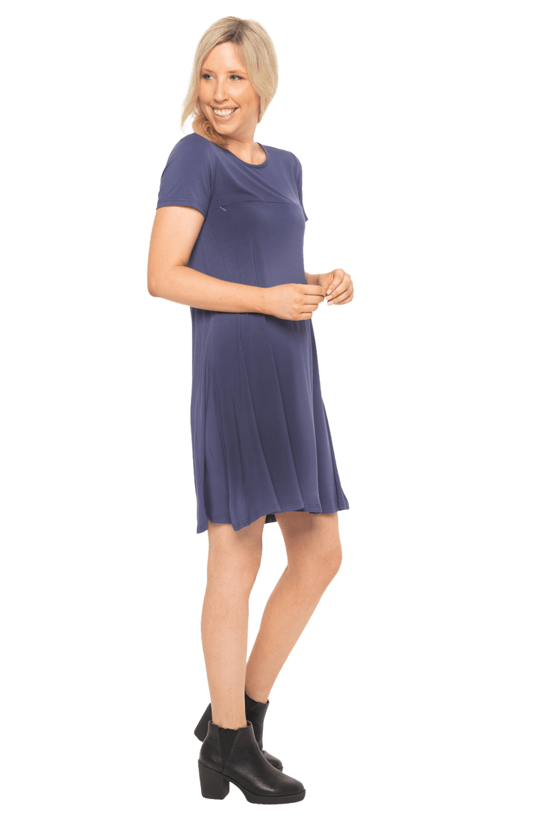 Model facing the side wearing navy blue, short sleeved, knee length, A-line dress. Features rounded neckline. Emma available in sizes 6-18