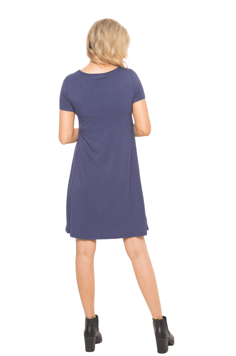 Model facing the back wearing navy blue, short sleeved, knee length, A-line dress. Features rounded neckline. Emma available in sizes 6-18