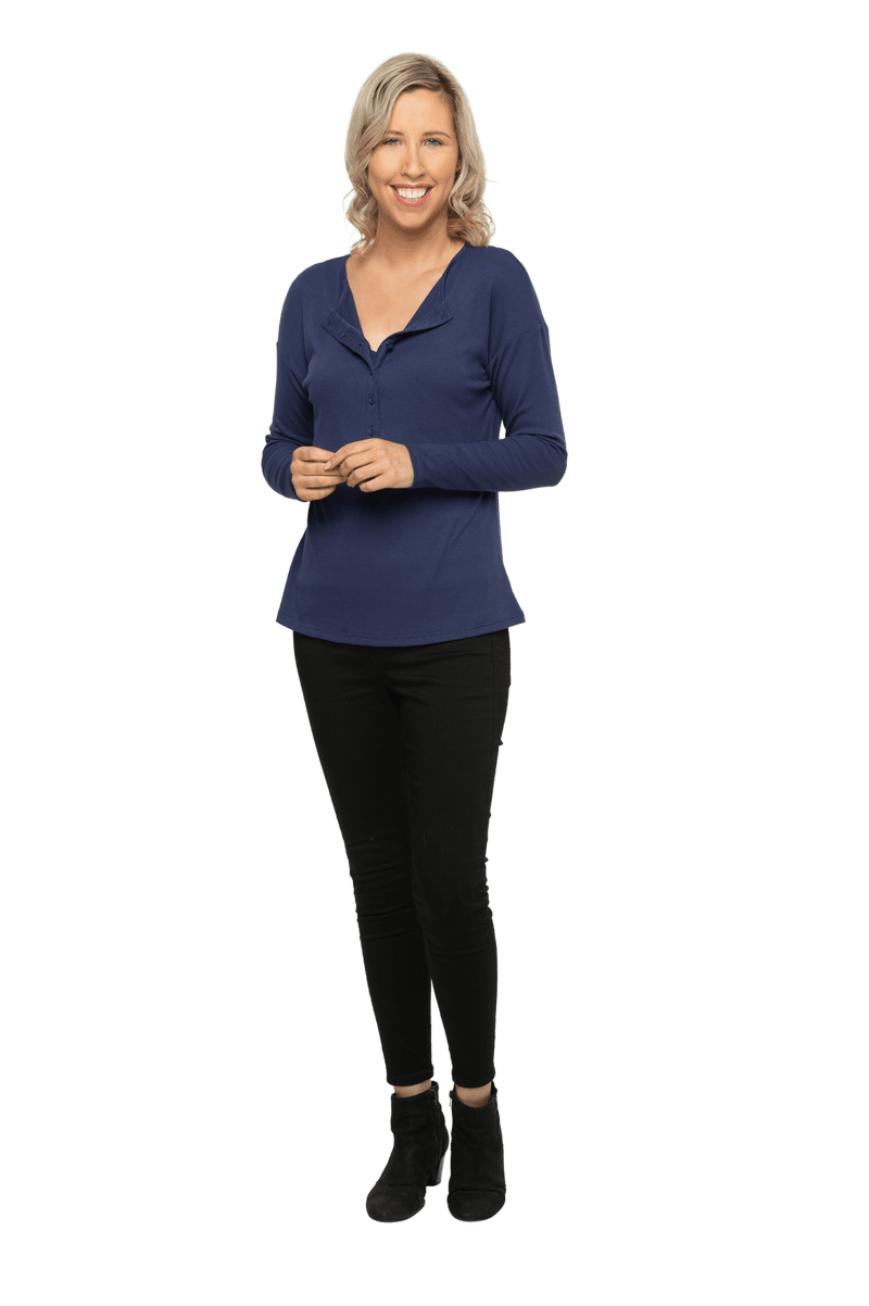 Petite model facing camera wearing navy blue, long sleeved henley top, slightly unbuttoned. Features button front and dropped shoulder. Hunter available in sizes 6-26