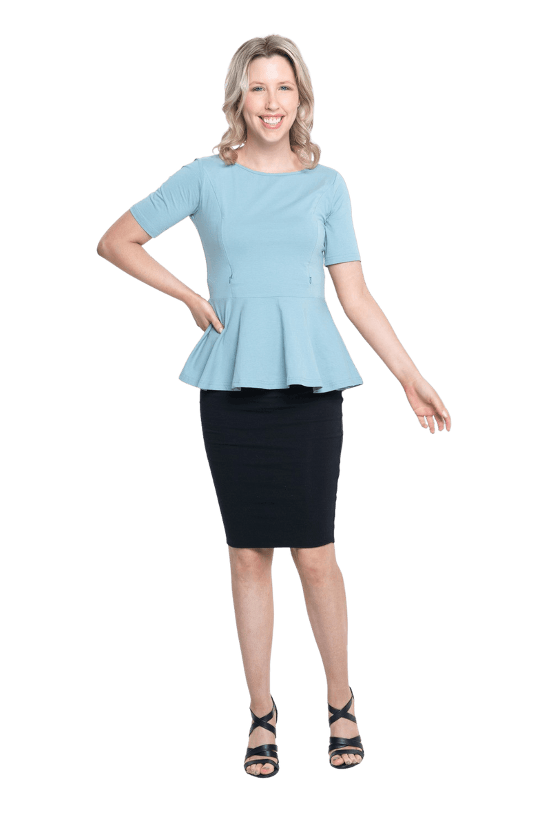 Petite model facing camera wearing light blue short sleeved top. Featuring rounded neckline and peplum tier under bust. Isla available in sizes 6-26