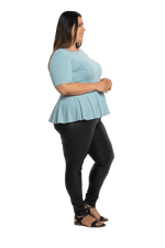 Curvy model facing the side wearing light blue short sleeved top. Featuring rounded neckline and peplum tier under bust. Isla available in sizes 6-26