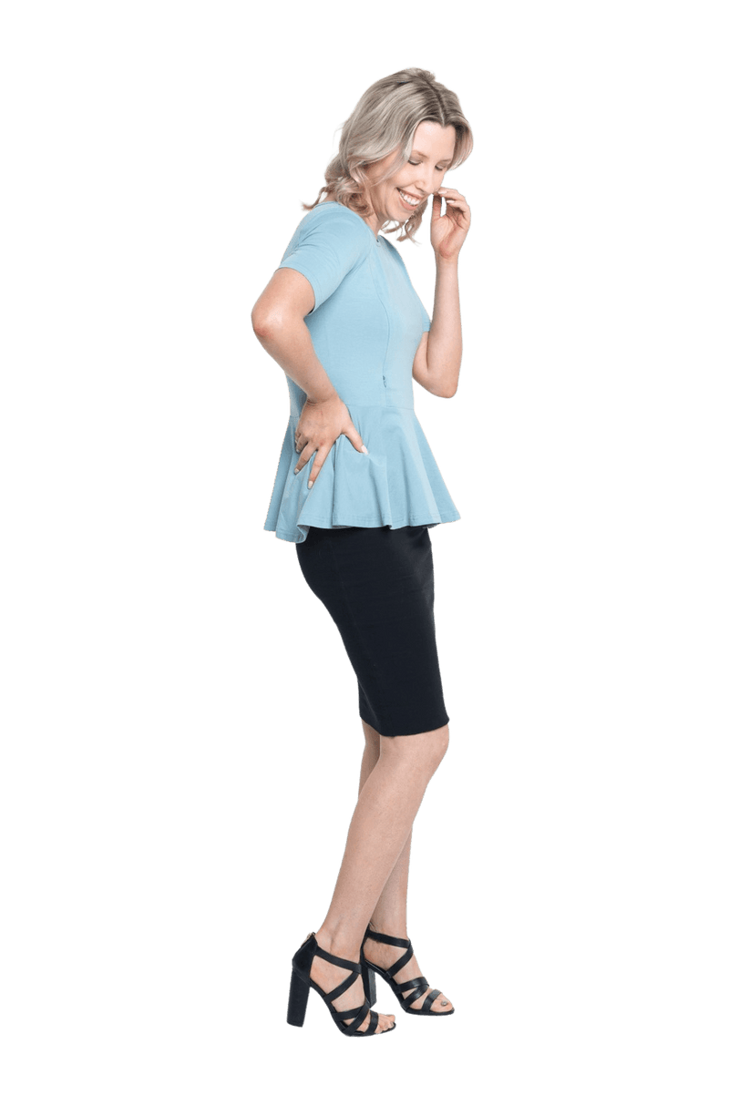 Petite model facing the side wearing light blue short sleeved top. Featuring rounded neckline and peplum tier under bust. Isla available in sizes 6-26