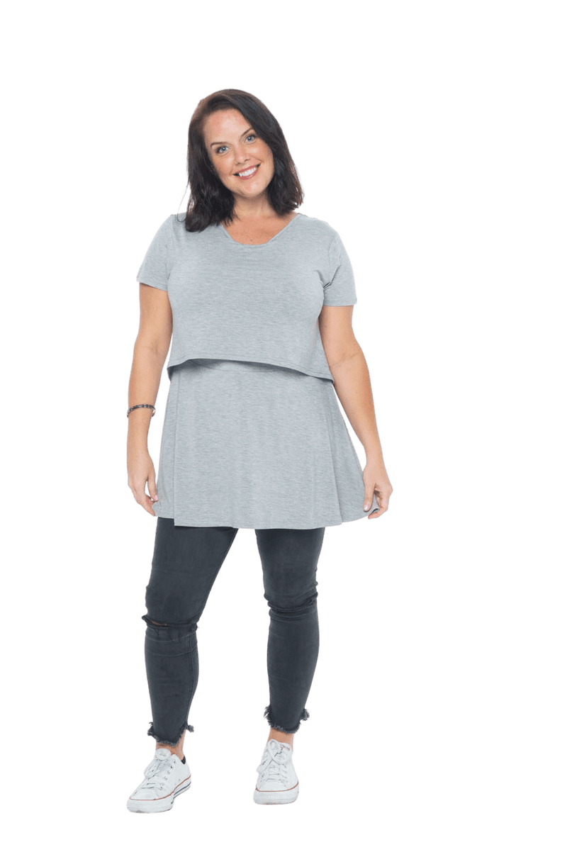 Model facing camera wearing grey, short sleeved top. Features rounded neckline. Jade available in sizes 6-18