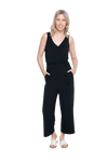 Petite model facing camera wearing black sleeveless, ankle-length, wide leg jumpsuit, featuring crossover neckline, waist belt and pockets. Jesse available in sizes 6-26