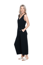 Petite model the side camera wearing black sleeveless, ankle-length jumpsuit, featuring crossover neckline, waist belt and pockets. Jesse available in sizes 6-26