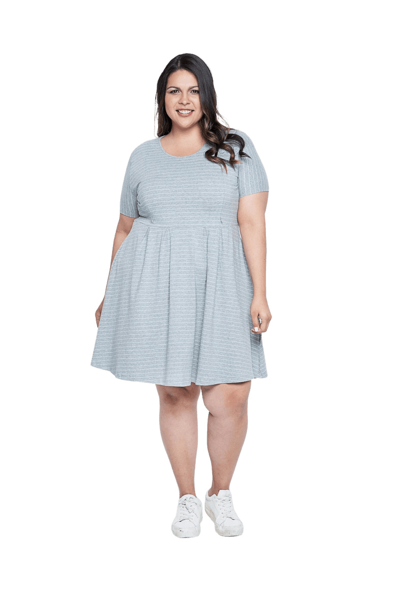 Curvy model facing camera wearing grey with white pin striped, knee length dress, featuring rounded neckline, fitted bodice, pleated A-line skirt and pockets. Kaitlyn available in sizes 6-26